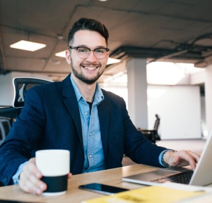 męzczyzna ubrany w garnitur siedzi przy komputerze