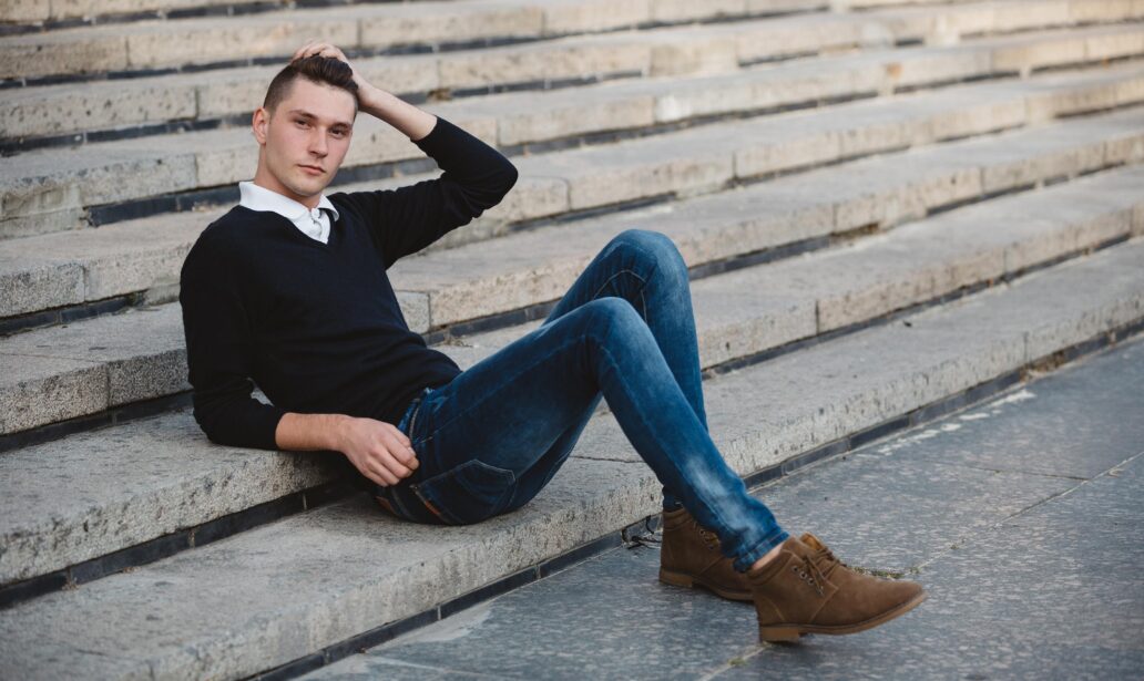 Młody mężczyzna w jeansach leży na schodach