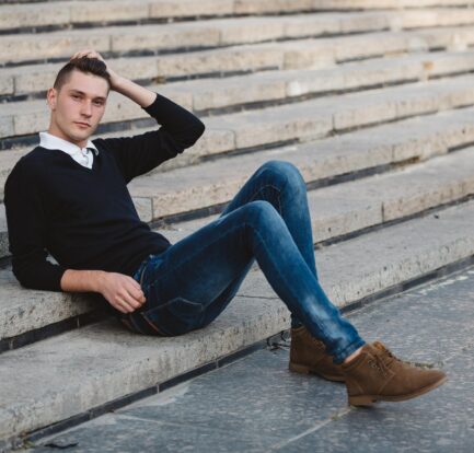 Młody mężczyzna w jeansach leży na schodach