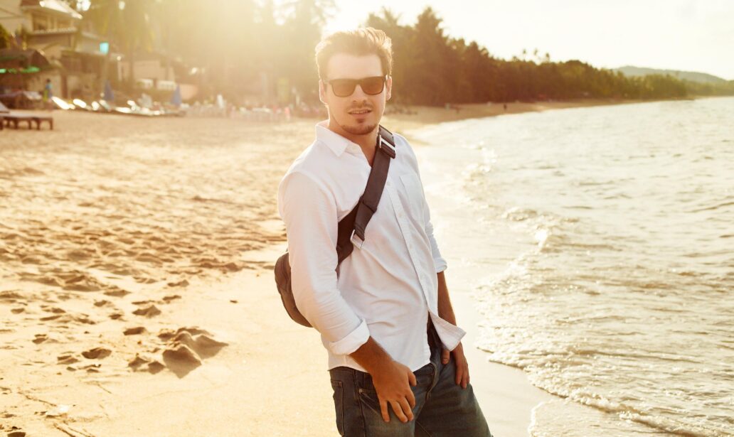 młody mężczyzna w białej koszuli na plaży