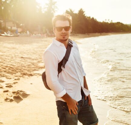 młody mężczyzna w białej koszuli na plaży